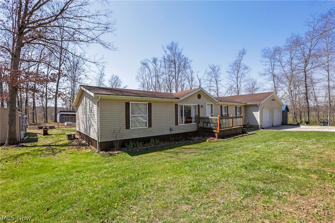 4502 Clover Road Cumberland, OH 43732 - Photo 3 of 38 Manufactured / mobile home featuring a deck, a garage, driveway, and a front yard
