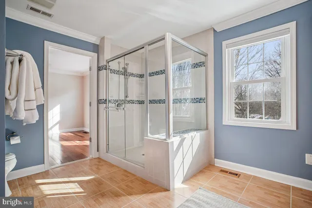 a bathroom with a glass shower door and a wooden floor