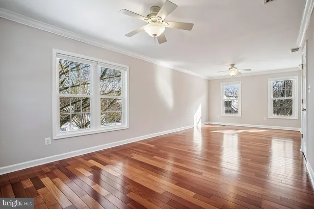 a view of an empty room with window and wooden floor