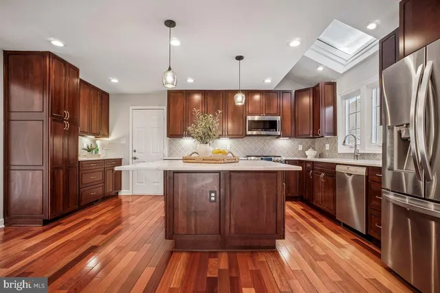 a kitchen with stainless steel appliances wooden floors wooden cabinets and refrigerator