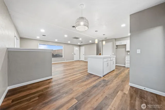 a large room with kitchen view and wooden floor