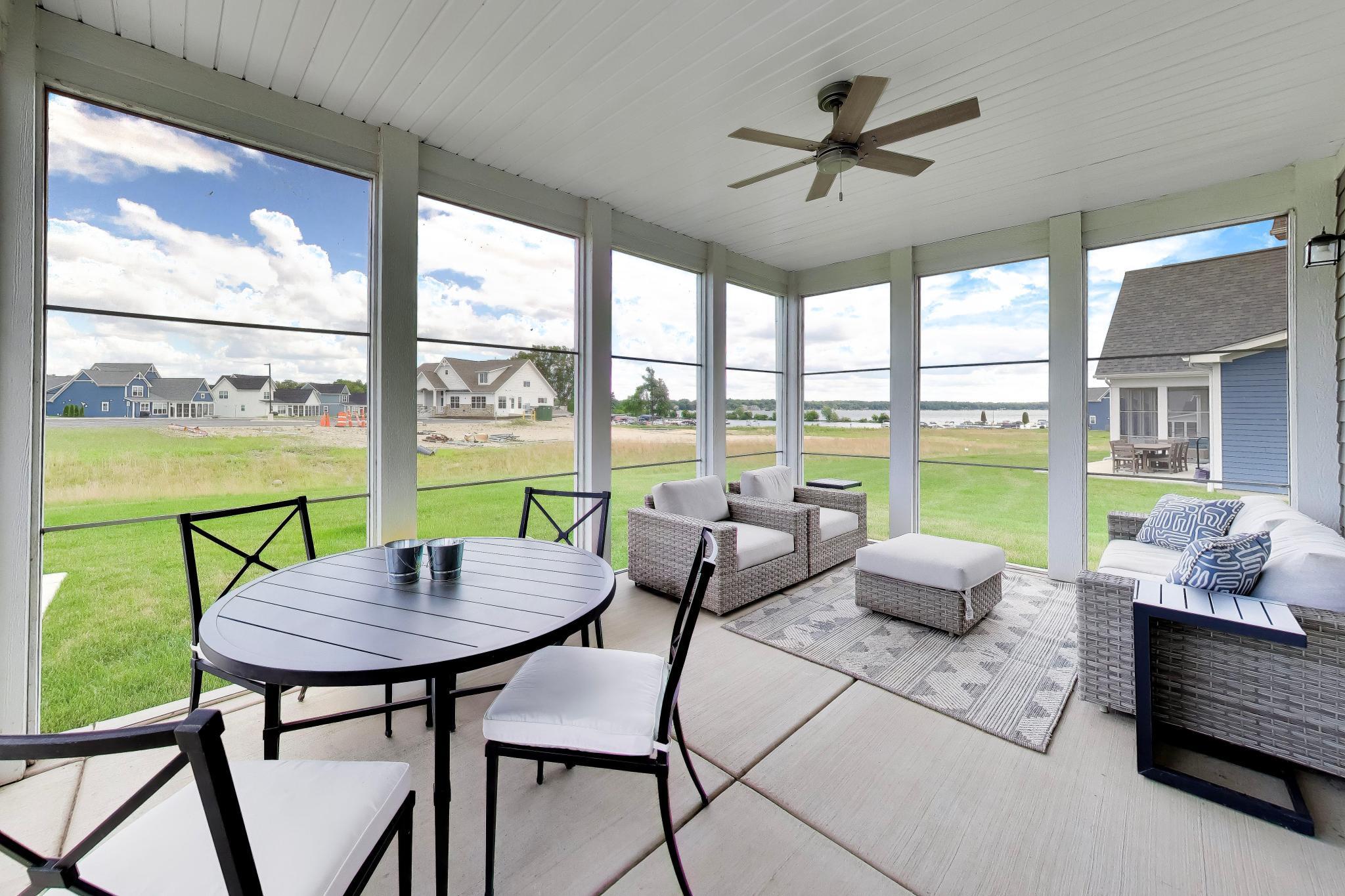 2730 Harbor Court Delavan, WI 53115 - Photo 5 of 47 Screened sunroom with Delavan Lake views, covered dining space, lounge seating, and ceiling fan.