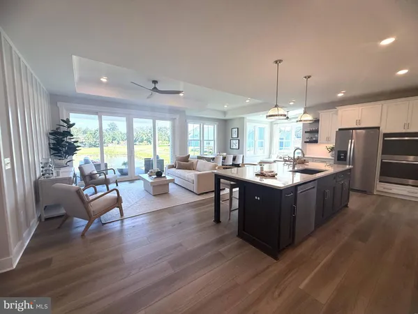 a large kitchen with a counter space a sink appliances and living room view