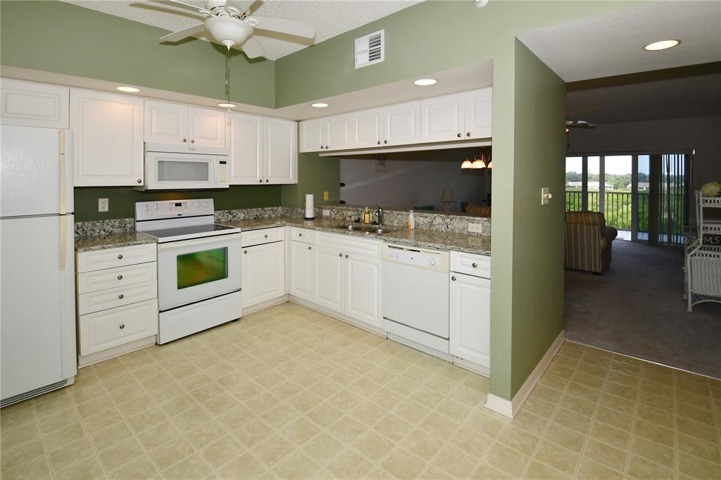 6450 Shoreline Drive, Unit 9405 St. Petersburg, FL 33708 - Photo 4 of 36 a kitchen with white cabinets and appliances