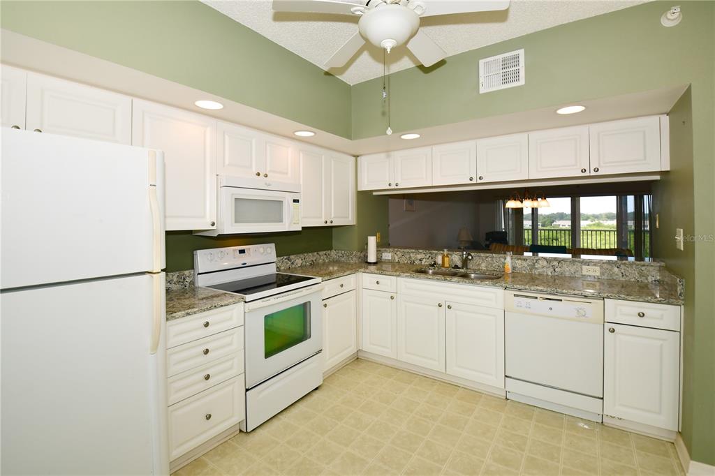 6450 Shoreline Drive, Unit 9405 St. Petersburg, FL 33708 - Photo 7 of 36 a kitchen with white cabinets and white appliances