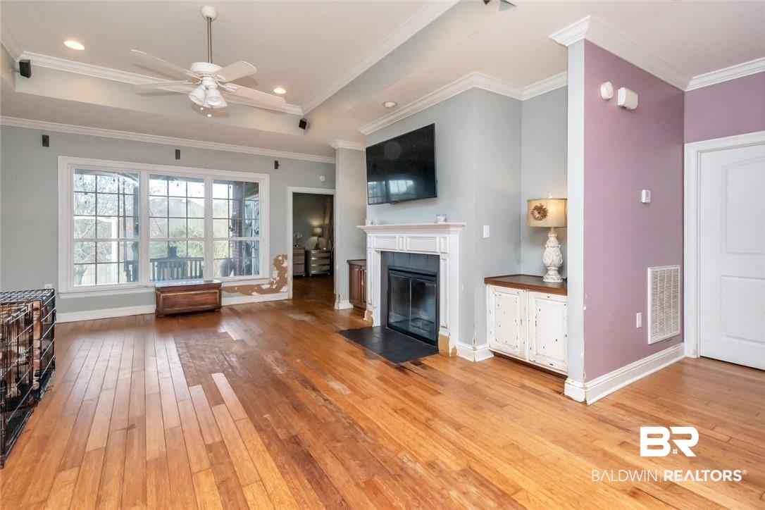 7170 Pierson Drive Mobile, AL 36619 - Photo 3 of 29 Unfurnished living room featuring a tray ceiling, light hardwood / wood-style flooring, crown molding, and ceiling fan