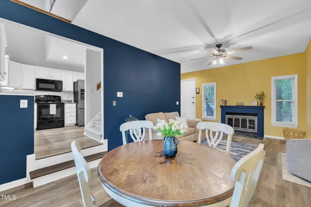 a dining room with furniture a rug a potted plant and wooden floor