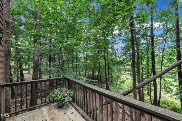a balcony with wooden floor and trees in the back