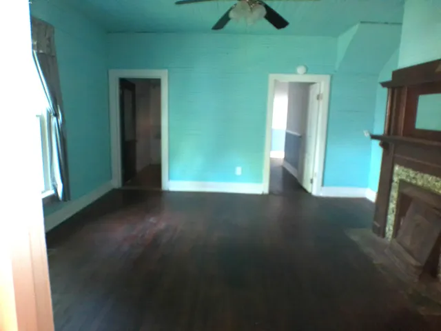 a view of a livingroom with wooden floor and a kitchen