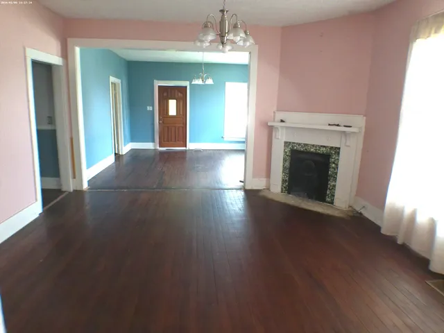 an empty room with wooden floor fireplace and windows