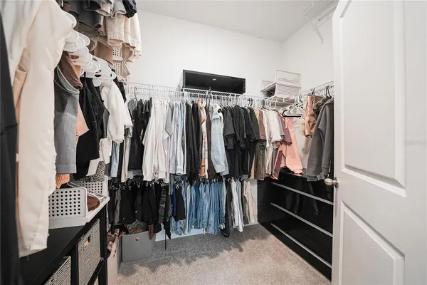 a view of walk in closet with clothes and shoes
