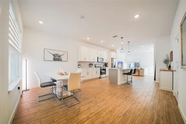 a living room with furniture and kitchen view with wooden floor