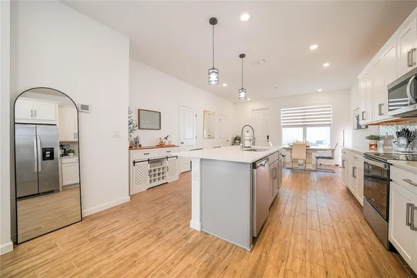 a kitchen with stainless steel appliances granite countertop a refrigerator a sink dishwasher a stove and white countertops with wooden floor