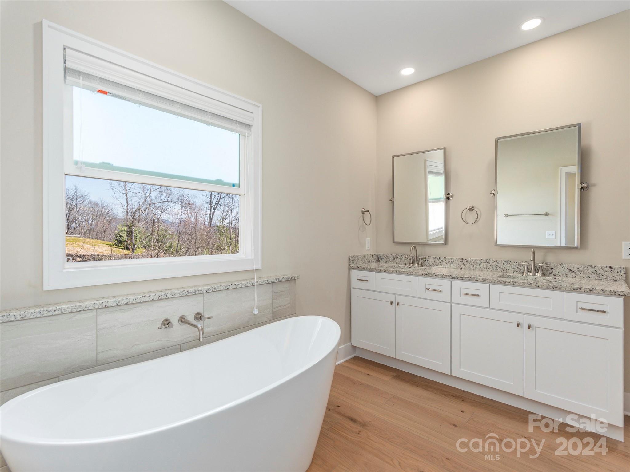 113 Millbrae Loop Hendersonville, NC 28791 - Photo 18 of 35 a bathroom with a granite countertop tub a sink and a window