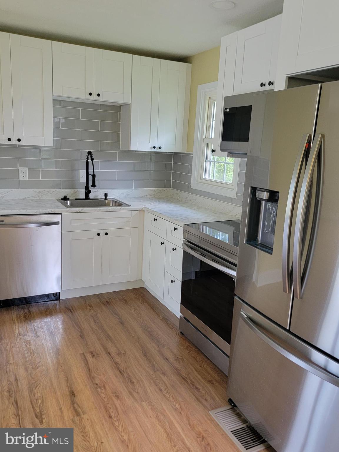 8300 Cathedral Avenue New Carrollton, MD 20784 - Photo 19 of 43 a kitchen with stainless steel appliances a stove a sink and white cabinets