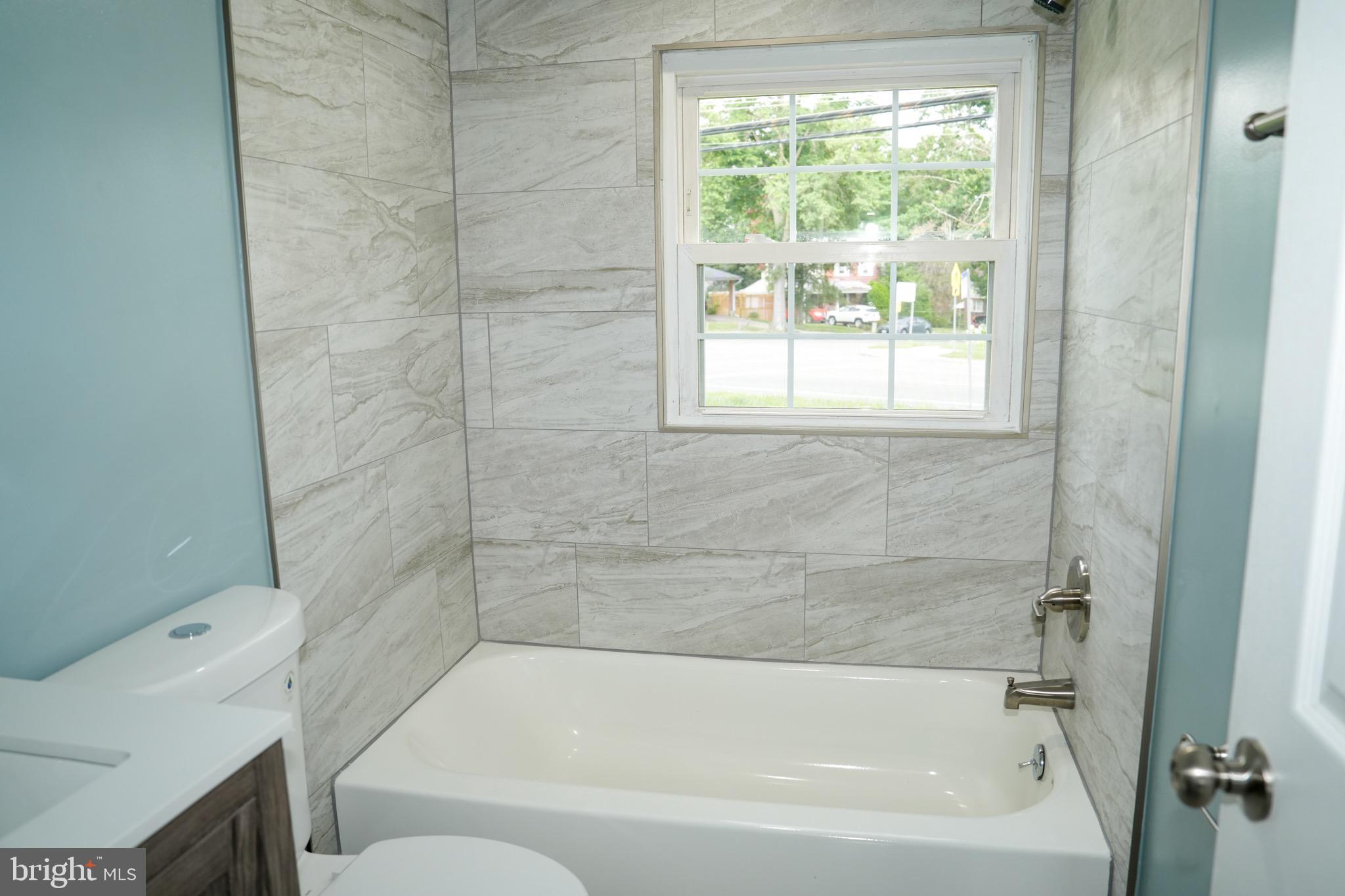 8300 Cathedral Avenue New Carrollton, MD 20784 - Photo 34 of 43 a bath tub sitting next to a white sink and a toilet