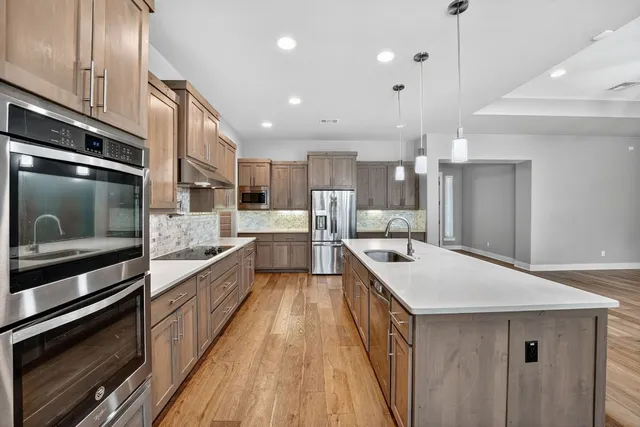 a large kitchen with stainless steel appliances kitchen island a large counter tops and a stove