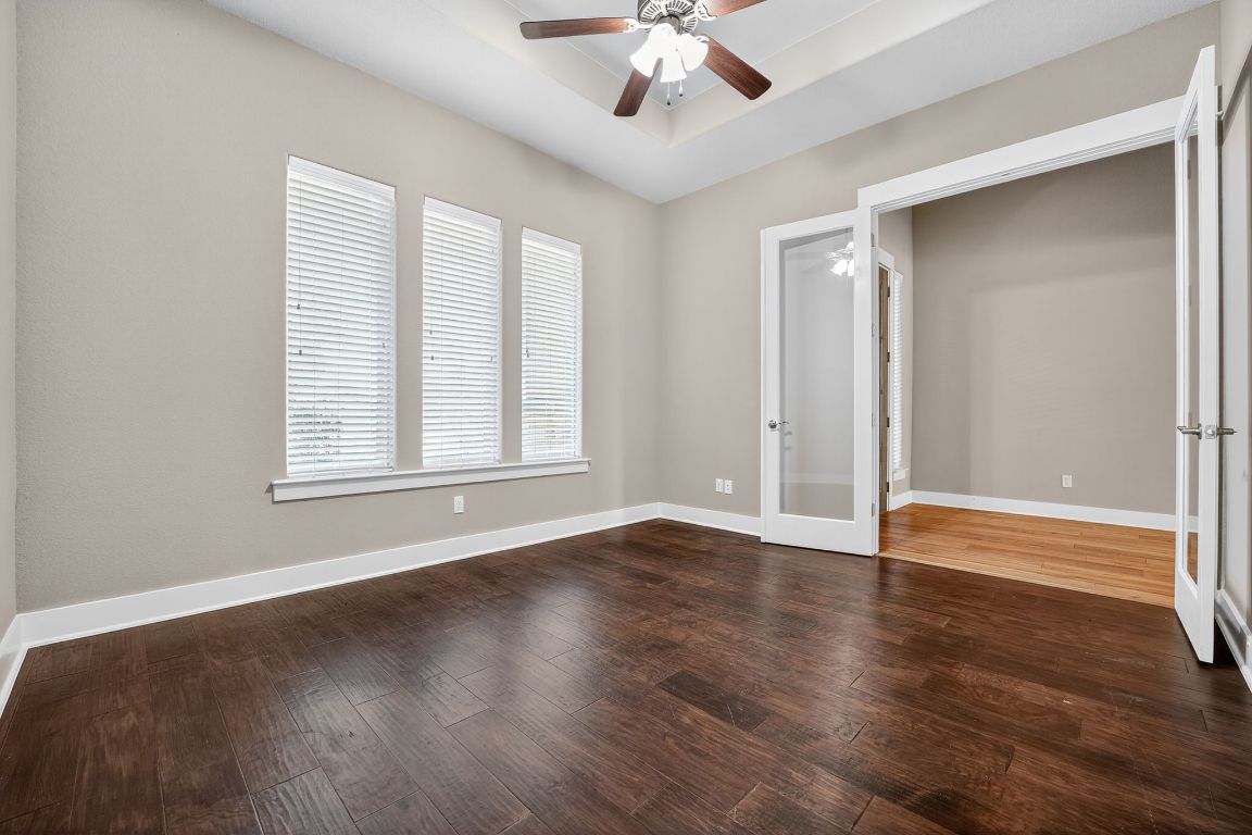 112 Sweetleaf Cove Georgetown, TX 78633 - Photo 17 of 28 an empty room with wooden floor chandelier fan and windows