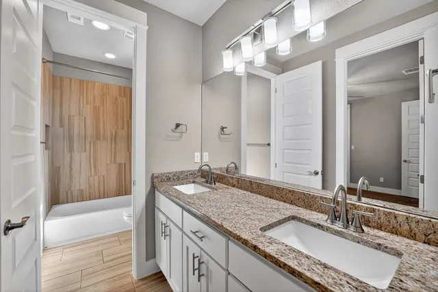 a bathroom with a granite countertop double vanity sink and a mirror