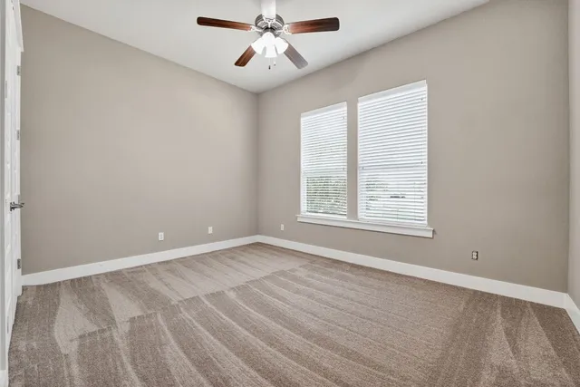 an empty room with windows and fan