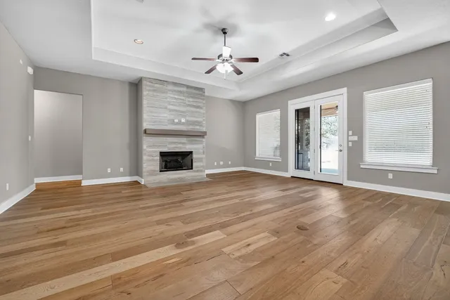 a view of an empty room with wooden floor fireplace and a window