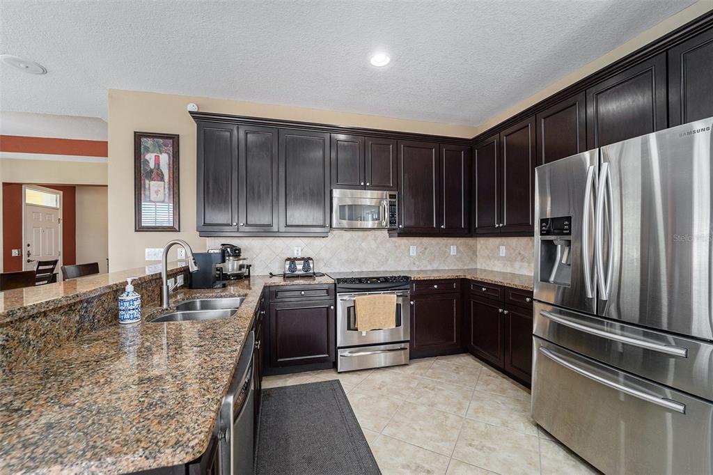 5516 Luminar Pointe Lane Apollo Beach, FL 33572 - Photo 13 of 34 a kitchen with stainless steel appliances granite countertop a refrigerator stove and oven
