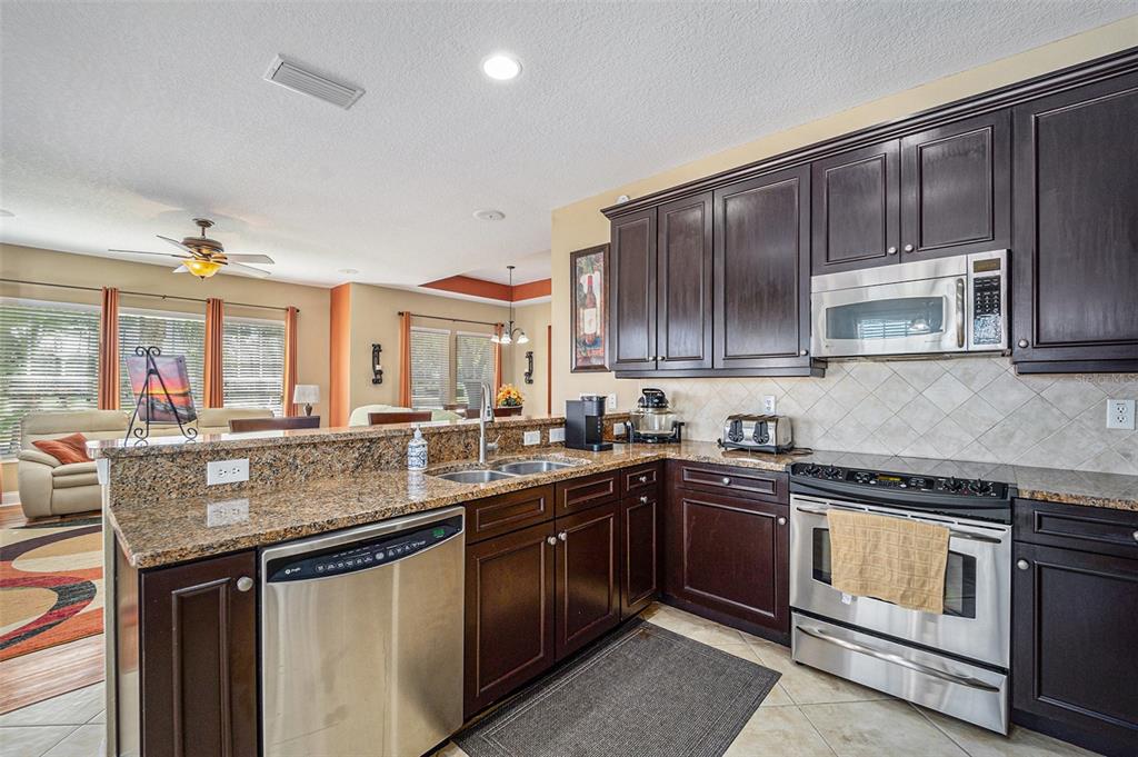 5516 Luminar Pointe Lane Apollo Beach, FL 33572 - Photo 14 of 34 a kitchen with kitchen island granite countertop stainless steel appliances a sink stove and cabinets
