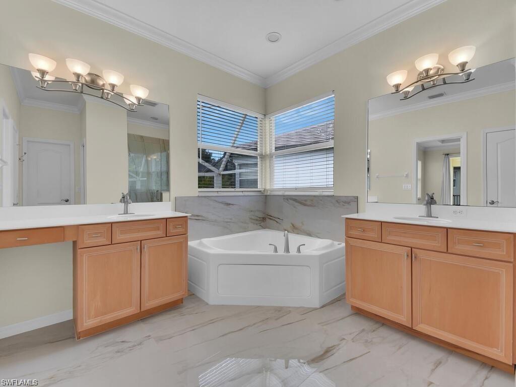 9983 Colonial Walk North Estero, FL 33928 - Photo 24 of 39 a bathroom with a tub a sink double vanity and a mirror
