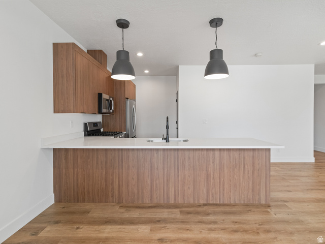130 East 7085th South, Unit 3 Midvale, UT 84047 - Photo 5 of 30 Kitchen featuring wood finish cabinets, a peninsula, light wood-style floors, and pendant lighting