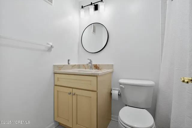 a bathroom with a granite countertop toilet sink and mirror