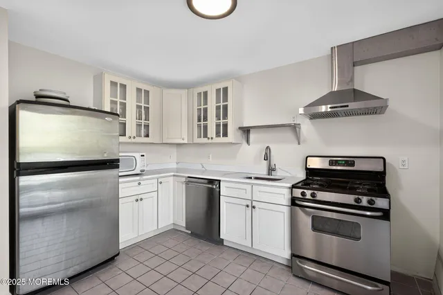 a kitchen with cabinets stainless steel appliances and wooden floor