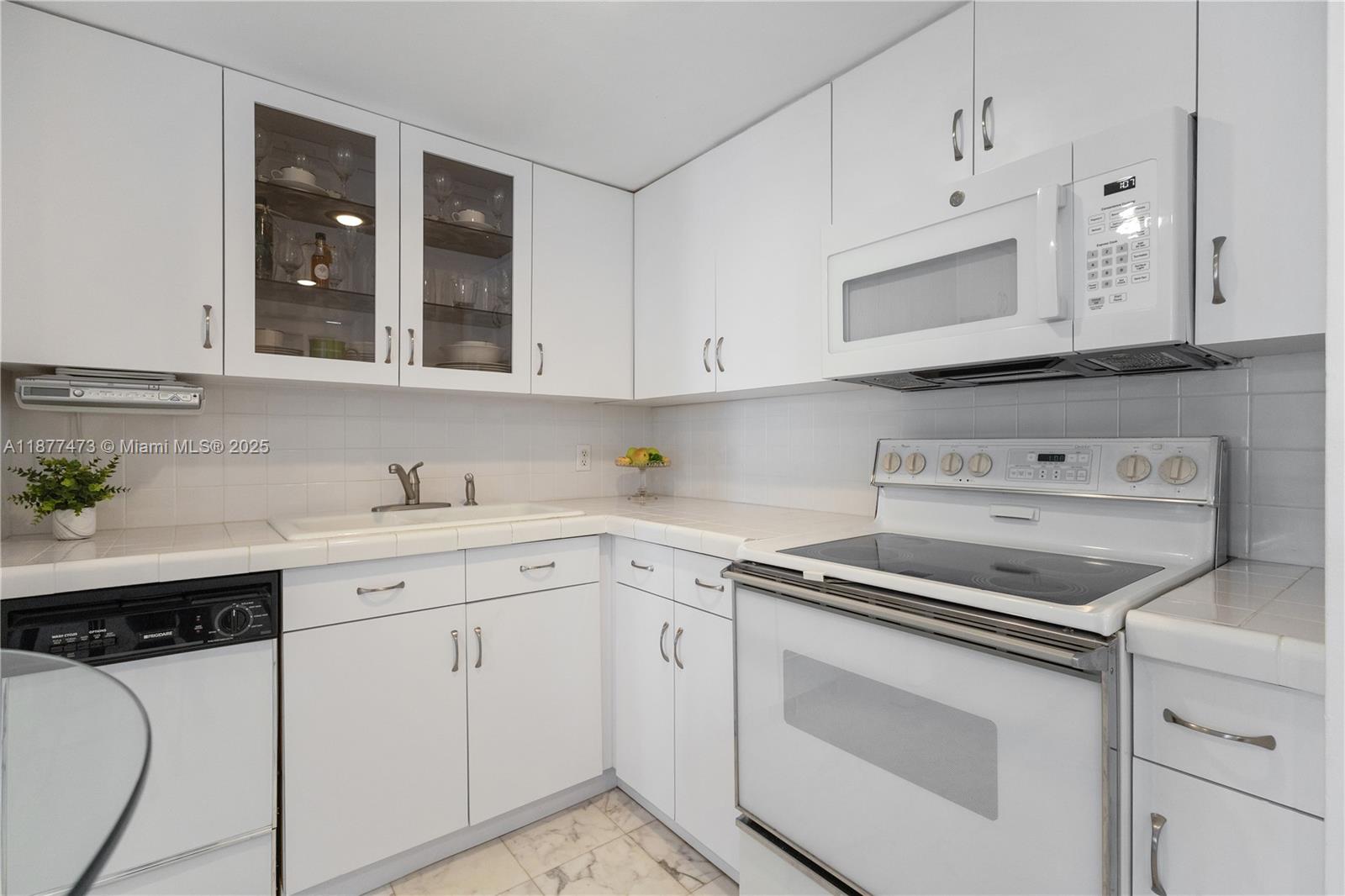 200 Southeast 15th Road, Unit 6F Miami, FL 33129 - Photo 23 of 38 a kitchen with white cabinets and white appliances
