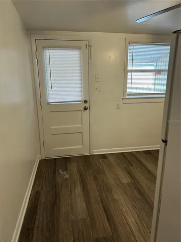 an empty room with wooden floor closet and windows