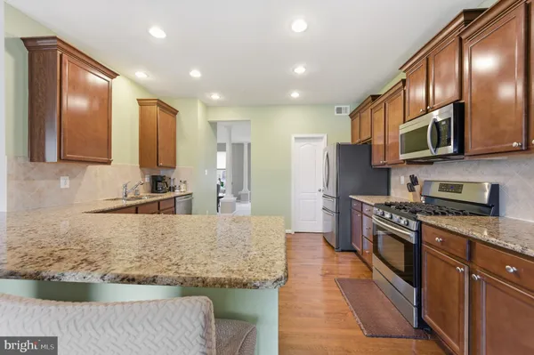 a kitchen with stainless steel appliances granite countertop a stove a sink and a microwave