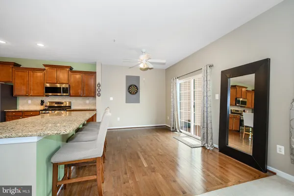 a view of a kitchen with kitchen island granite countertop wooden floor and a refrigerator
