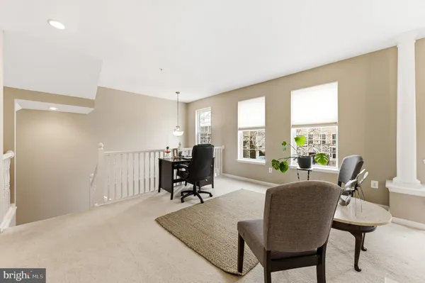 a living room with furniture two large windows and a dining table