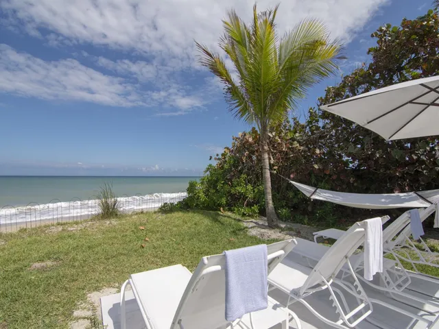a view of a backyard with lawn chairs under an umbrella