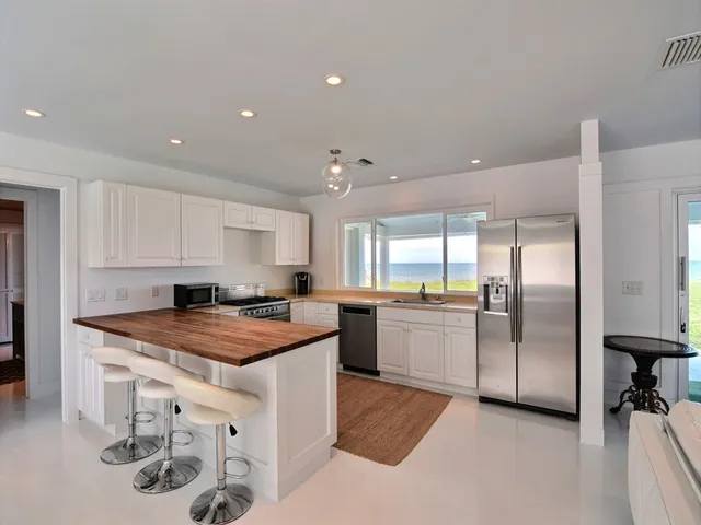 a kitchen with stainless steel appliances granite countertop a sink a stove a refrigerator and white cabinets