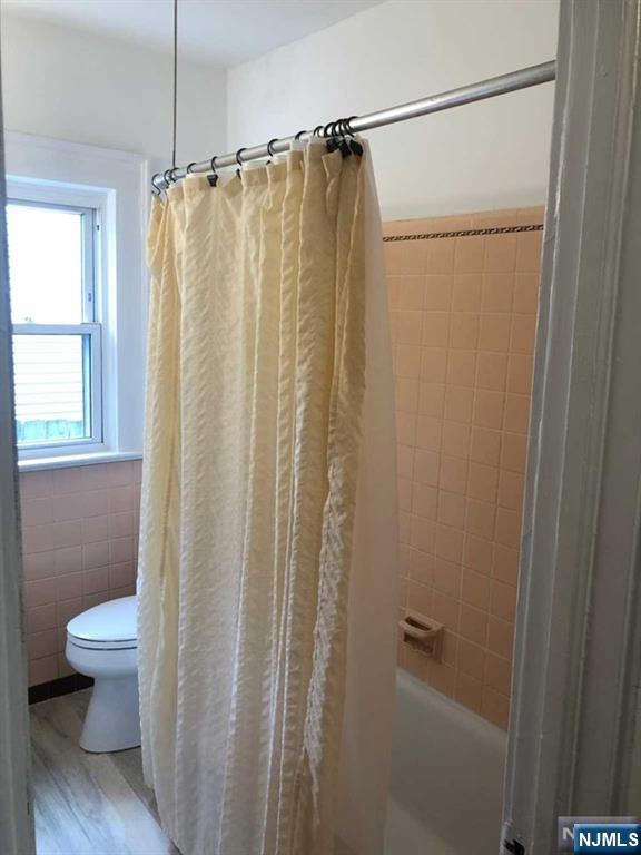 15 East Van Ness Avenue, Unit 1 Rutherford, NJ 07070 - Photo 19 of 25 a bathroom with a shower curtain and a toilet