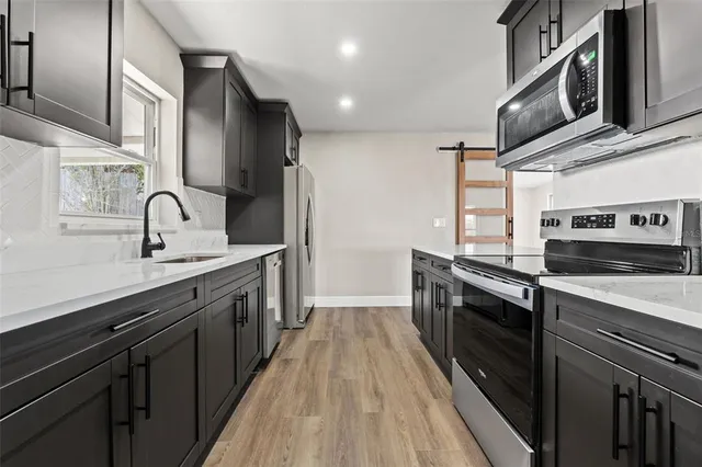 a kitchen with stainless steel appliances granite countertop a sink a stove and a refrigerator