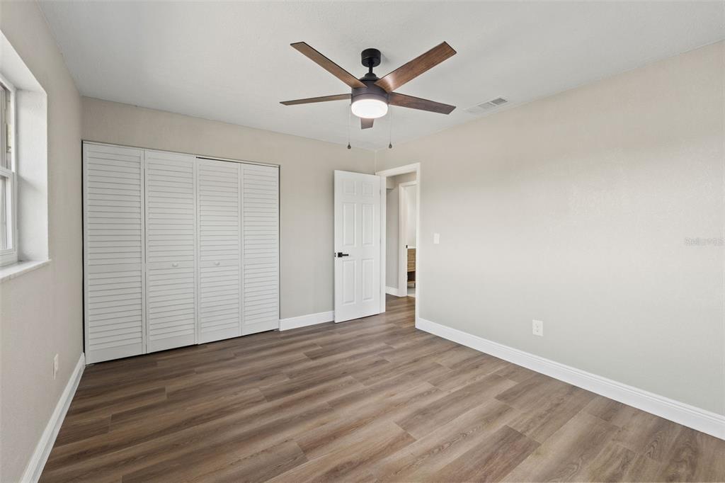1173 Cobblestone Drive Spring Hill, FL 34606 - Photo 30 of 39 an empty room with wooden floor ceiling fan and windows