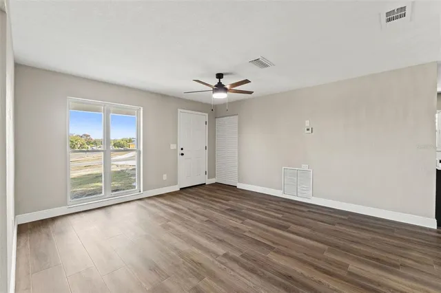 a view of an empty room with wooden floor and a window