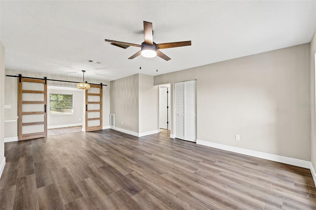 1173 Cobblestone Drive Spring Hill, FL 34606 - Photo 10 of 39 an empty room with wooden floor ceiling fan and windows