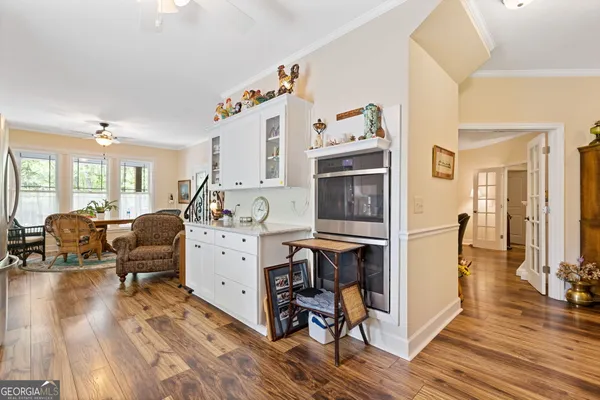 a living room with furniture a dining table wooden floor and a large window
