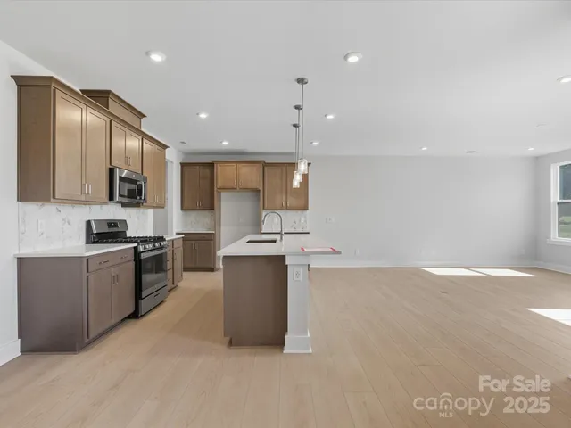 a large kitchen with stainless steel appliances granite countertop a stove a sink a refrigerator and a microwave