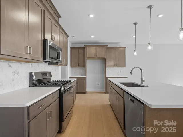 a kitchen with stainless steel appliances granite countertop a sink a stove and a refrigerator