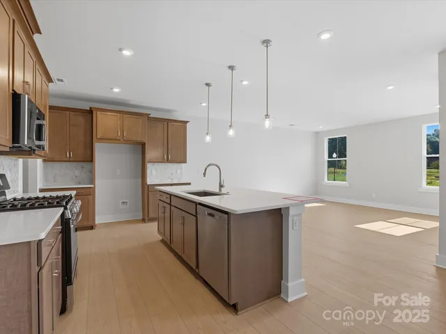 a kitchen with stainless steel appliances granite countertop a sink a stove and a refrigerator