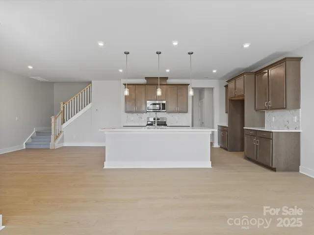 a white kitchen with kitchen island a sink and a stove top oven