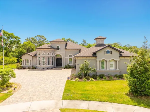 a view of a big house with a big yard and large trees