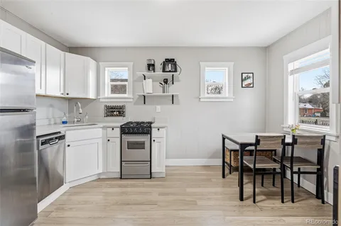 a kitchen with stainless steel appliances granite countertop a stove top oven a sink a dining table and chairs with wooden floor